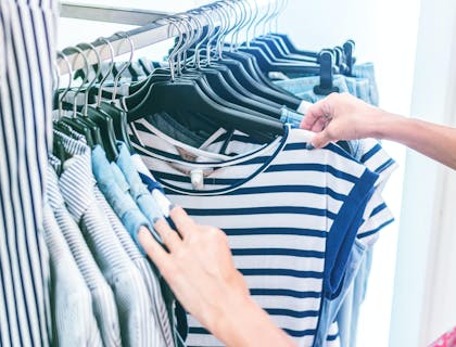 Woman browsing through shirts at a clothing business.