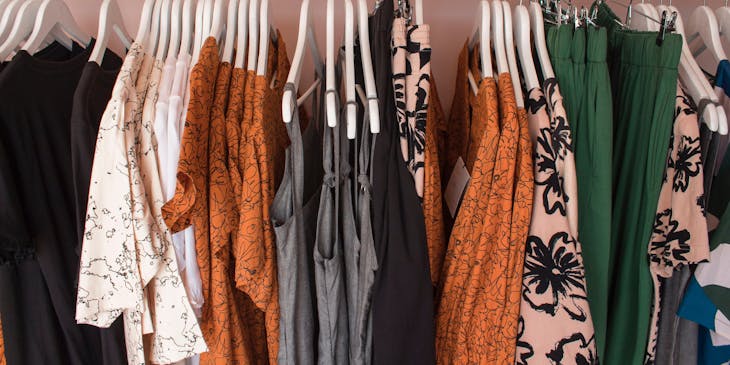 Rack of clothing containing bright and dark pieces at a clothing rental business.