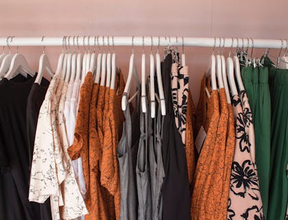 Rack of clothing containing bright and dark pieces at a clothing rental business.