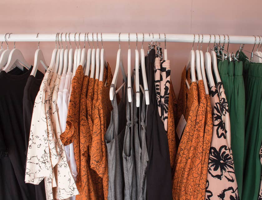 Un rack de vêtements contenant des vêtements clairs et foncés dans un magasin de location de vêtements.