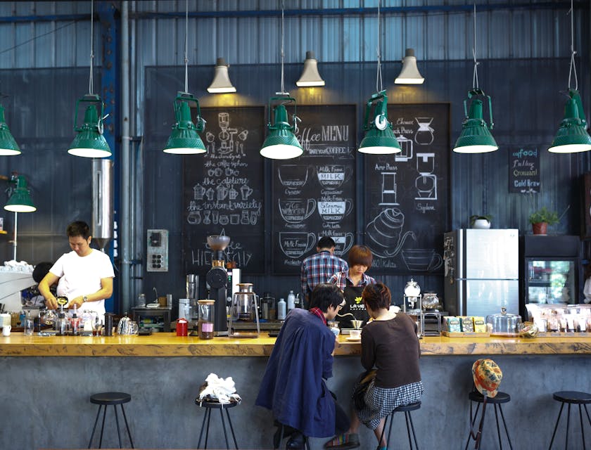 A coffee shop with a barista serving a pour at the counter.