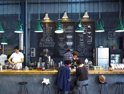 Uma cafeteria com um barista servindo pessoas no balcão.