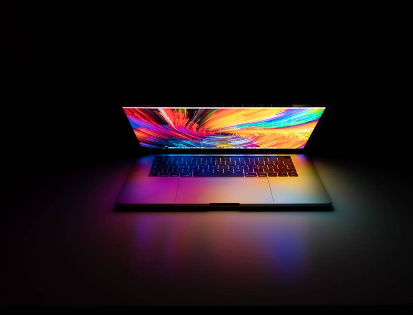 Um computador MacBook Pro em cima de uma mesa em uma sala escura.