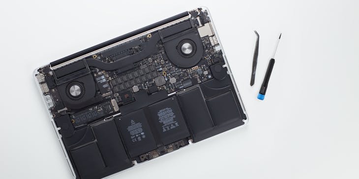 laptop without plastic case beside two tools at a computer repair business