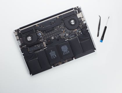laptop without plastic case beside two tools at a computer repair business