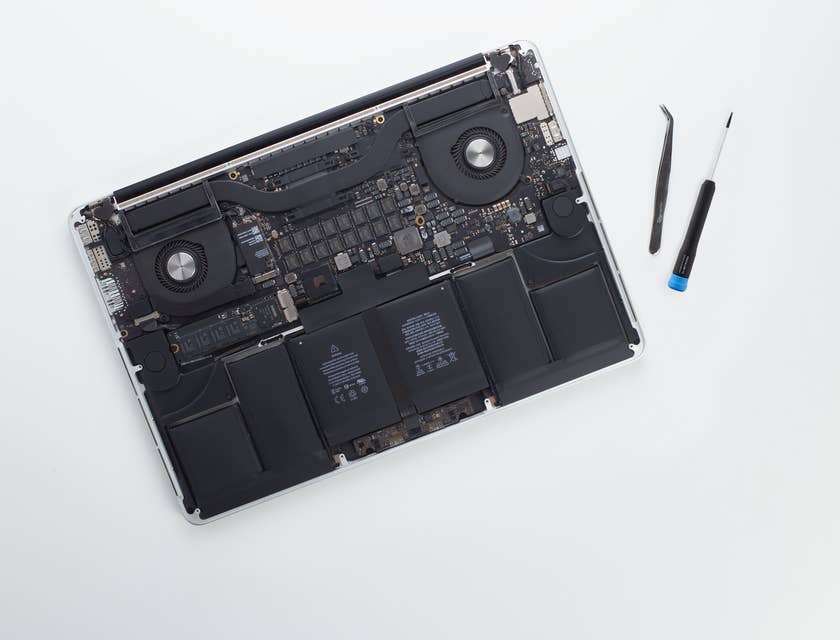 Un ordinateur portable sans sa coque en plastique à côté de deux outils dans une entreprise de réparation d'ordinateurs.