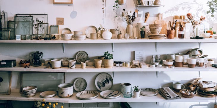 White shelves holding crockery, picture frames, vases, and plants at a concept shop.