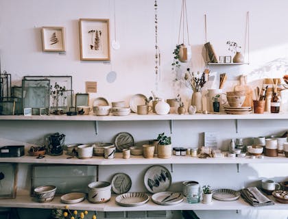 White shelves holding crockery, picture frames, vases, and plants at a concept shop.