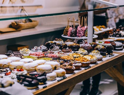 Una exhibición de donas, pasteles y otros dulces en una confitería.