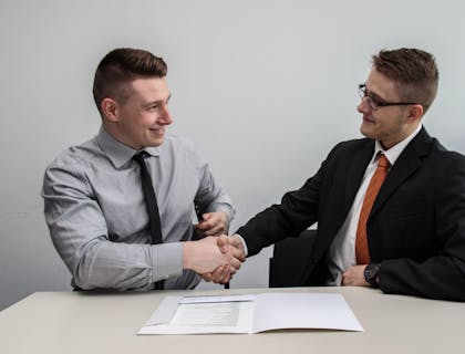 Dos hombres dándose la mano después de firmar un contrato en un negocio de derecho contractual.