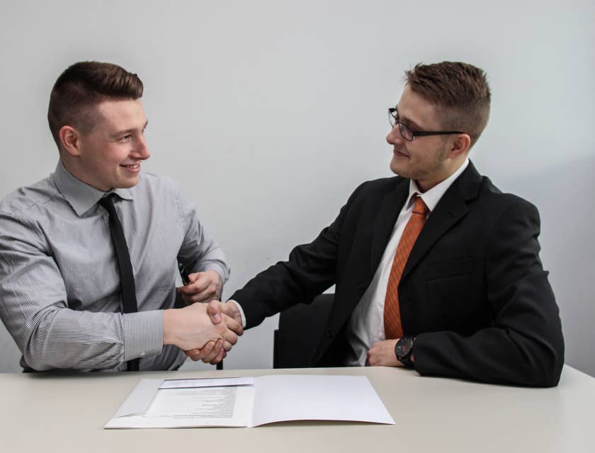 dois homens se cumprimentando após assinar um contrato