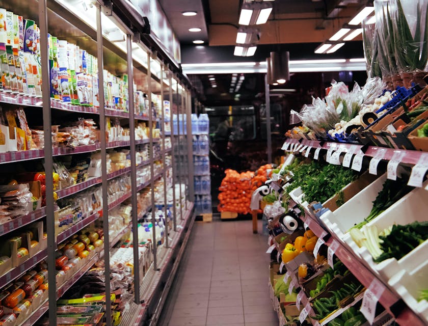 Primo piano di un carrello con banchi frigo da supermercato sullo sfondo.