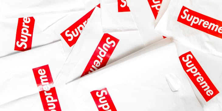 Image of folded shopping bags with Supreme brand name on the front.