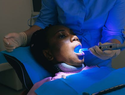 Dentista usando fotopolimerizador em um paciente em uma clínica de odontologia estética.