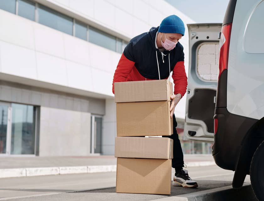 Entregador carregando pacotes em um carro de entrega.
