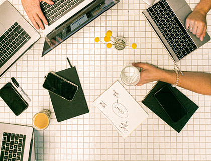 Desk full of laptops and working professionals in a coworking environment.