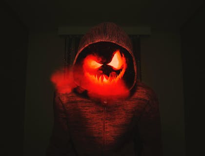 Un’inquietante zucca intagliata con una felpa rossa.