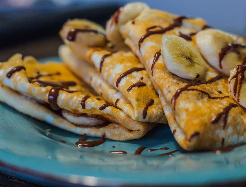 Tre crepes con Nutella e banana sopra un piatto di una creperia.