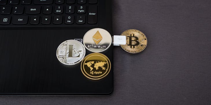 Coins depicting different cryptocurrencies on a laptop
