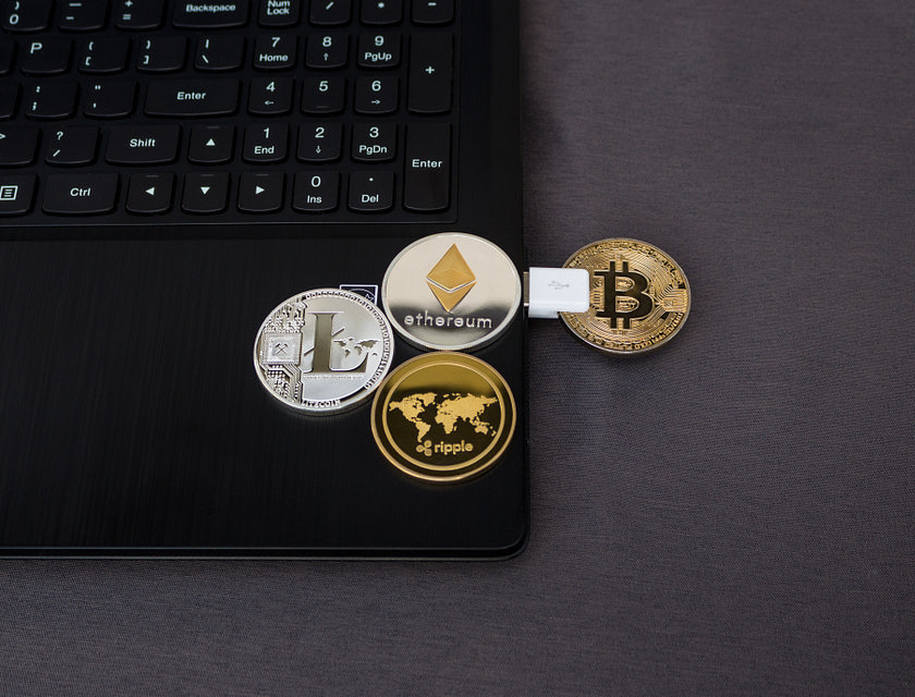 Moedas representando diferentes criptomoedas em cima de um laptop.