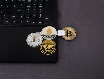 Coins depicting different cryptocurrencies on a laptop