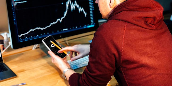 Man using a scientific calculator to analyze data on a computer screen.