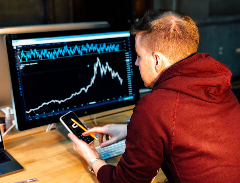 Hombre usando una calculadora científica para analizar datos en una pantalla de computadora.