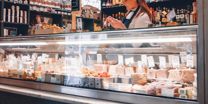 Mujer de pie detrás de un mostrador de delicatessen.