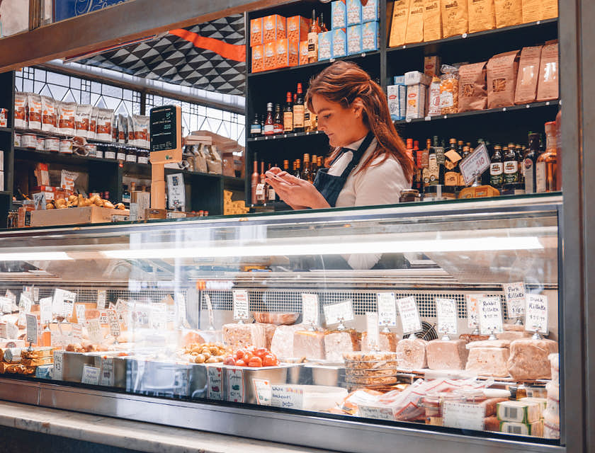 A woman standing behind a deli counter.