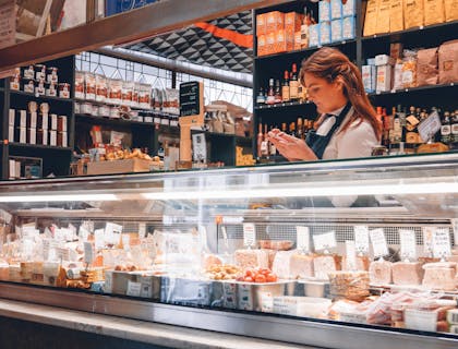 Una commessa che sta dietro al banco di una gastronomia o alimentari.