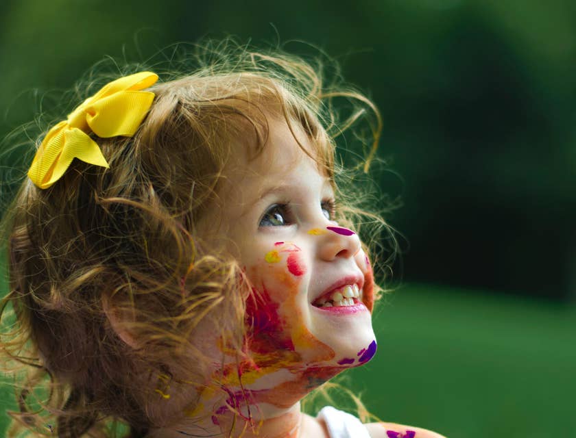 Una bambina deliziosa piena di colori sul viso e le braccia.