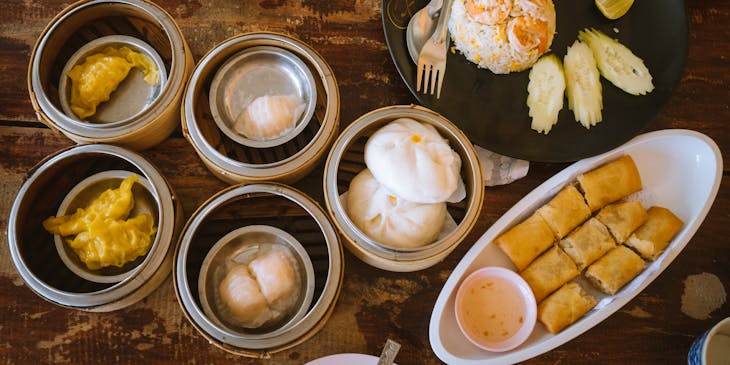Table packed with various Chinese dim sum dishes.