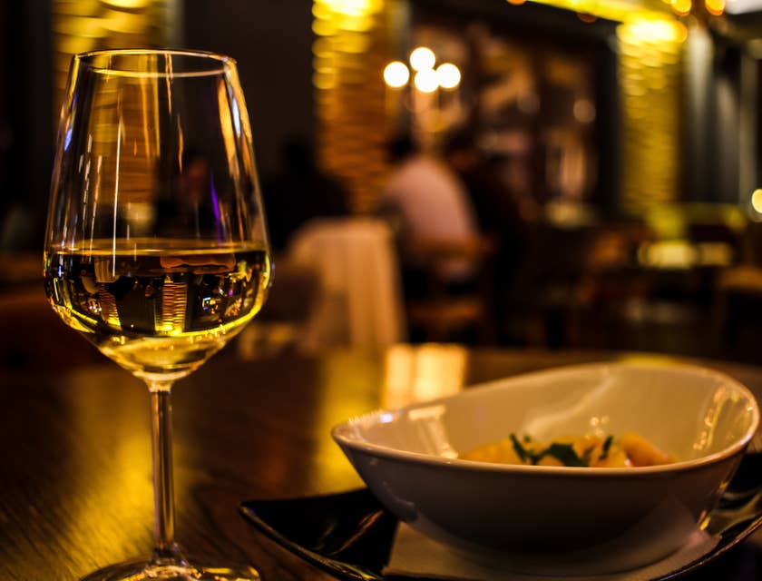 Verre de vin blanc à côté d'un bol blanc dans un dîner-spectacle faiblement éclairé.