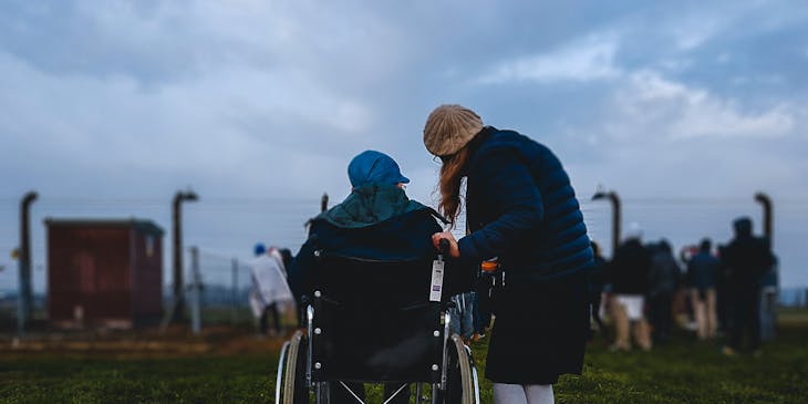 Woman standing next to a person in a wheelchair.