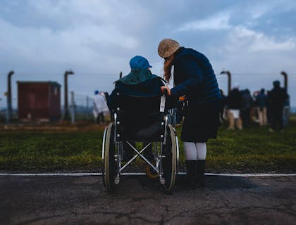 Mujer de pie junto a una persona en silla de ruedas en un despacho de abogados para discapacitados.