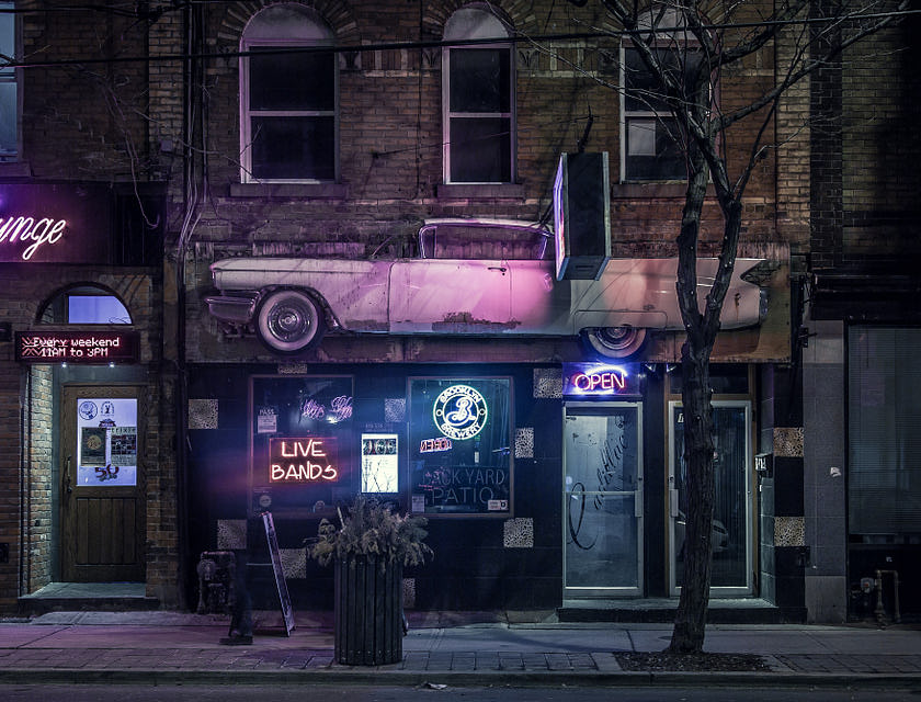 L'entrée d'un bar de quartier avec enseignes au néon.