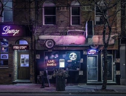 Entrada de um barzinho com letreiro neon.