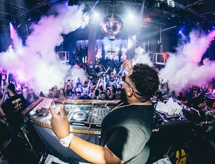 Un DJ entretiene al público dentro de una fiesta.