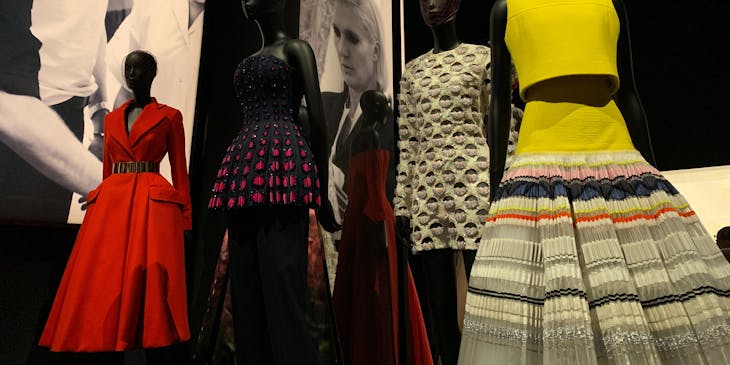 Showroom with various dresses on mannequins with black and white photos in the background.