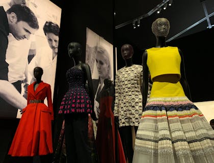 Un showroom avec diverses robes sur mannequins avec des photos en noir et blanc en arrière-plan.