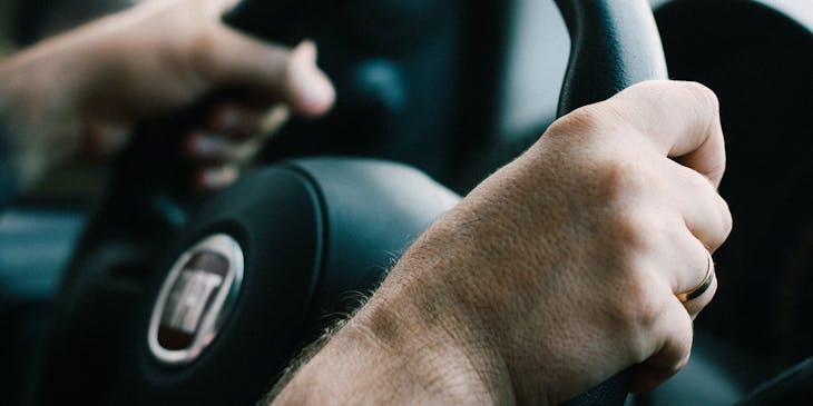 A person gripping a steering wheel while driving.