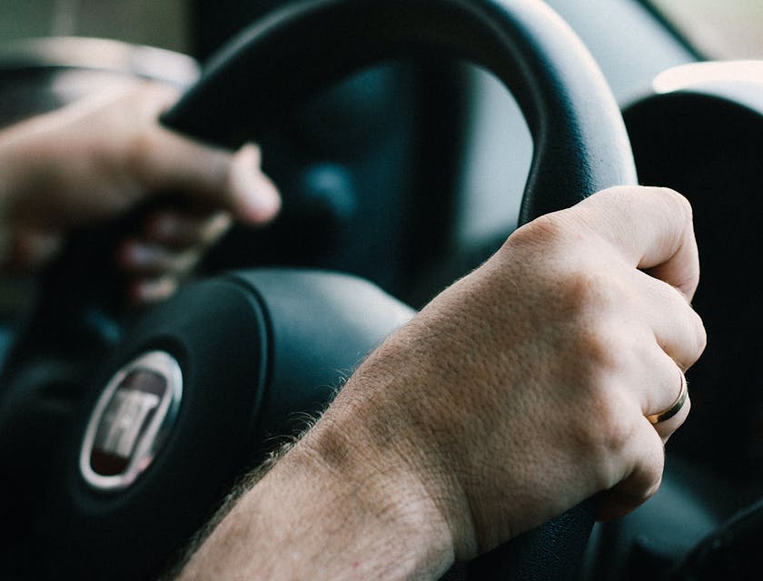 Ein Fahranfänger greift mit beiden Händen das Lenkrad eines Fahrschulautos.