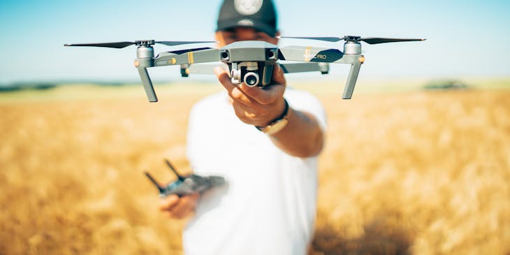 Man holding a drone while standing in a field.