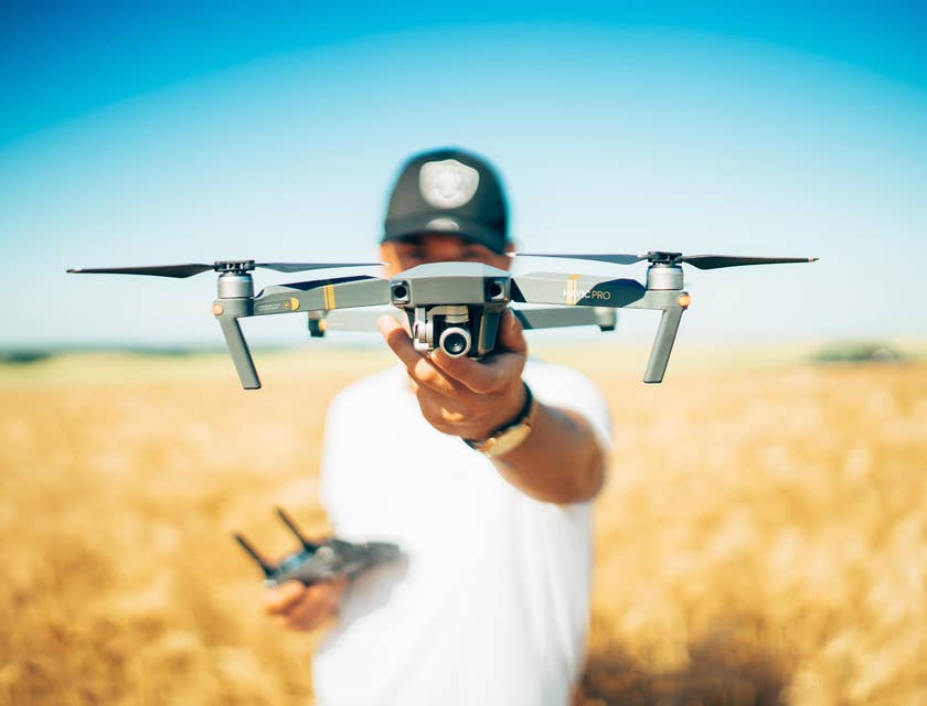 Una persona che tiene in mano un drone che sta per sollevarsi in un campo.