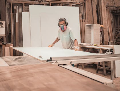 Un hombre levantando una pieza de tablaroca en su empresa de tablaroca.