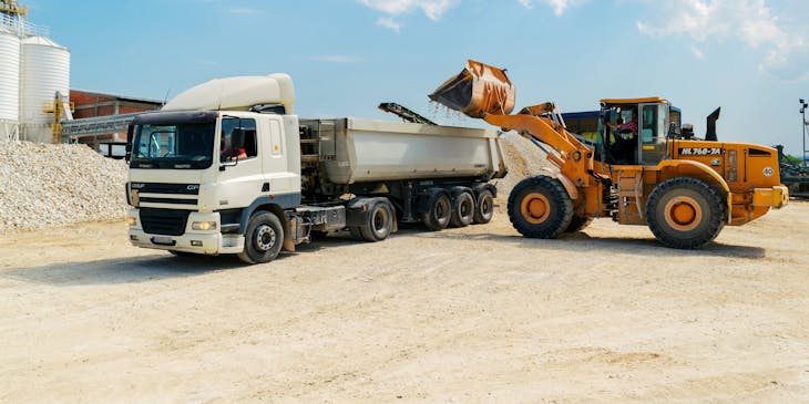 Front end loader next to a white dump truck.