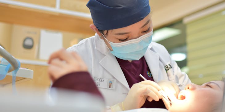 Ear, nose, and throat doctor examining a patient's mouth.