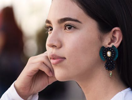 Una ragazza di profilo che indossa un orecchino pendente maxi.