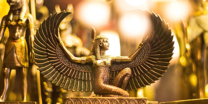 Gold winged, Egyptian goddess figurine kneeling with wings spread.