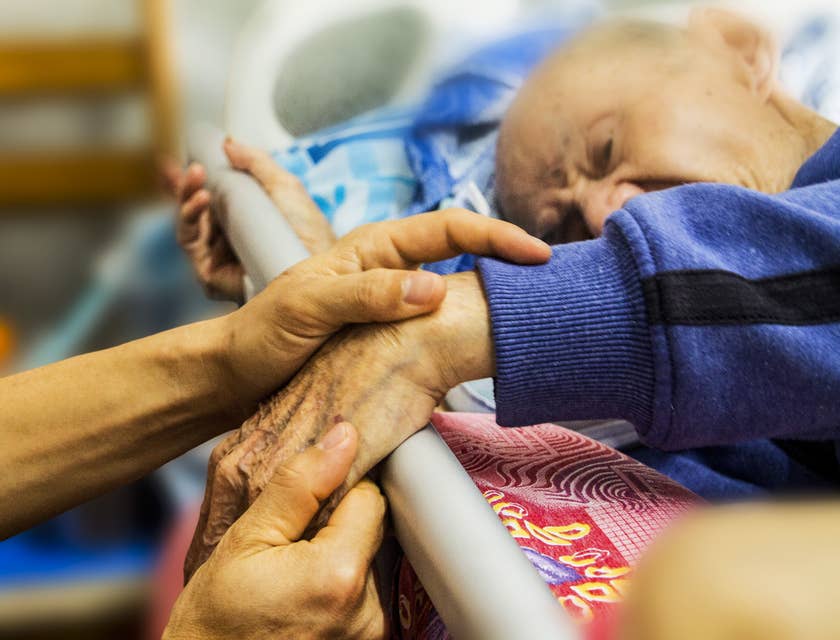 Une personne tenant la main d'un homme âgé nécessitant des services de planification des soins pour personnes âgées.